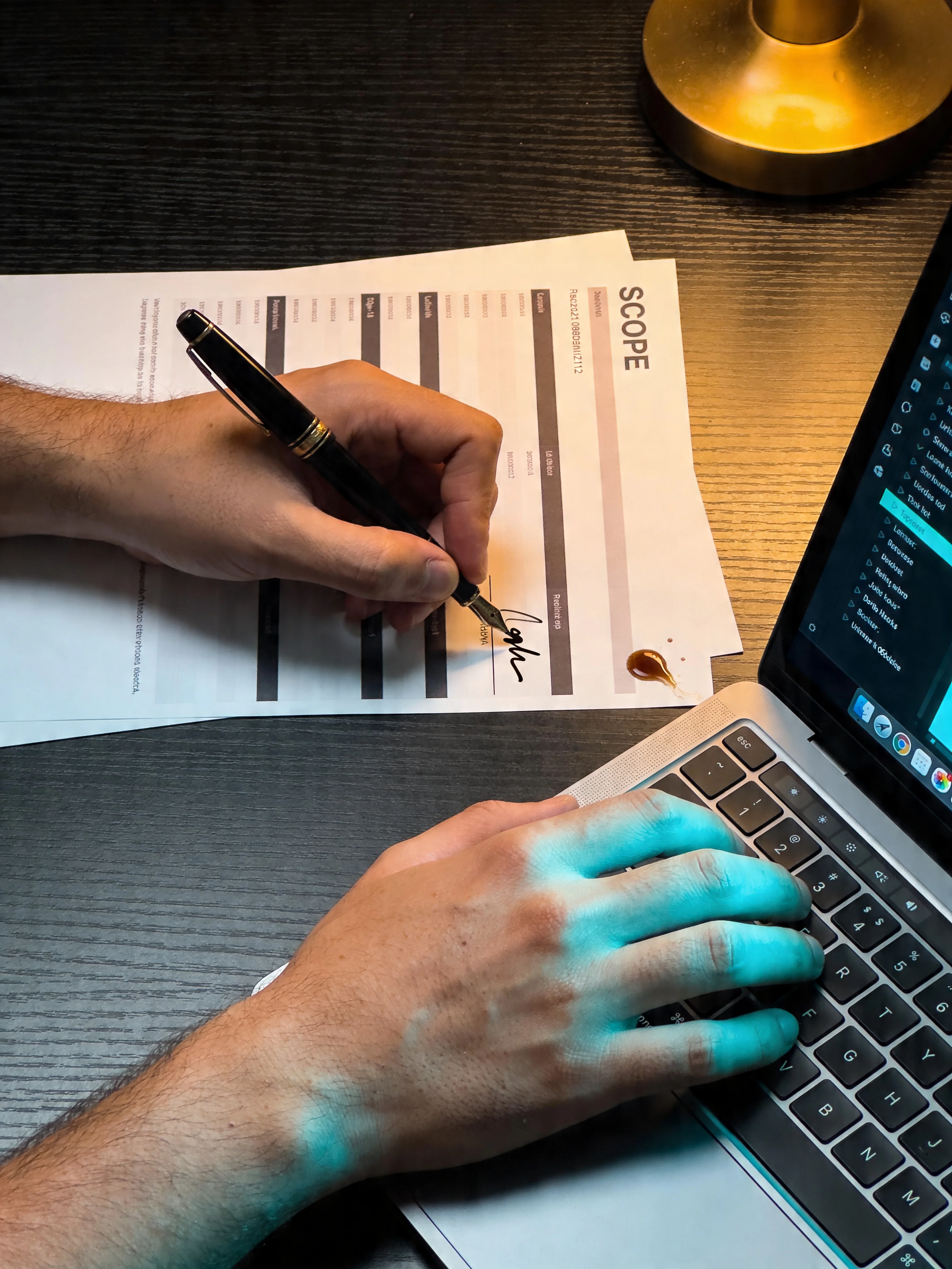 Fountain pen signing a Scope document beside a laptop with cyan glow on the hand, FICAITION engagement kickoff